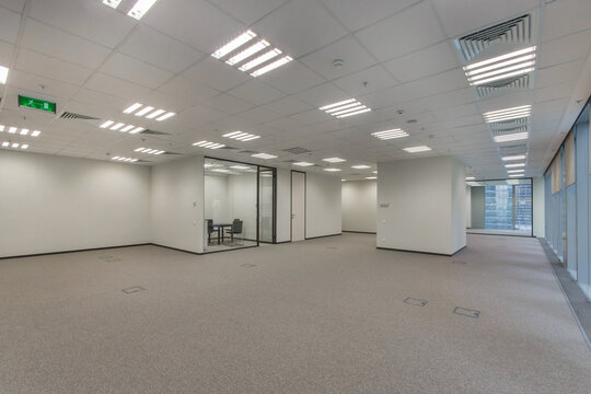 An empty office space in bright colors, unfurnished, with an office with a glass wall.