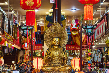 Vibrant interior of Chinatown shop with giant golden buddha surrounded by wind chimes