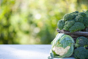 Cauliflower and broccoli in a basket on a natural green background, space for text
