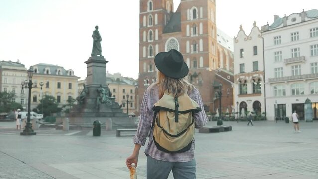 Real view of traveller woman walking on old Market Square in Krakow holding tourist map. Travel and active lifestyle concept. High quality photo. High quality FullHD footage