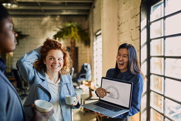 Young Asian female designer showing her building plans progress to her coworkers in a startup company office