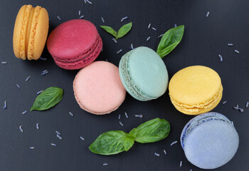 Six colorful macarons on a black background