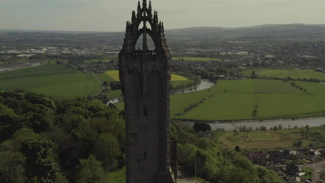 Aerial shot of National Wallace Monument tourist attraction with houses and green fields in background in Scotland, UK