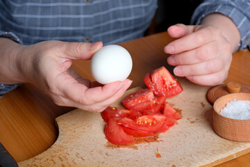 Hands of an elderly woman showing a white boiled egg