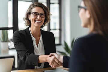 Happy mid aged business woman manager handshaking greeting client in office. Smiling female executive making successful deal with partner shaking hand at work - Generative AI