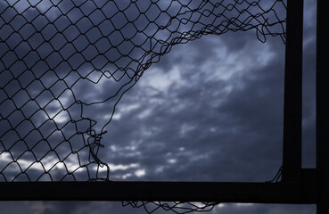Opening in metallic net fence. isolated on blue sky background. Challenge. uncertainty....