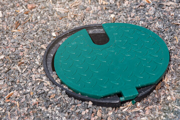 Obraz na płótnie Canvas A plastic hatch in the garden covering the connection point for the irrigation hose. A protective hatch in the garden for connecting water and watering plants.