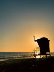 Sunset on the beach with the silhouette of a lifeguard stand