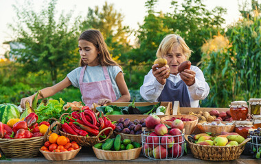 Grandmother and granddaughter sell vegetables and fruits at the farmers market. Selective focus.