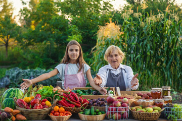 Grandmother and granddaughter sell vegetables and fruits at the farmers market. Selective focus.