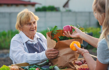 old woman farmer sells vegetables and fruits at the farmers market. Selective focus.