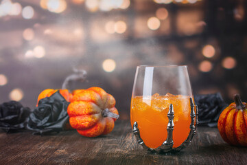 Halloween orange cocktail in spooky skeletons hand glasses