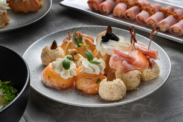 Holiday savory profiteroles with caviar, cream cheese and dill on a white plate on a white background. A plate on a festive table. Clouse-up