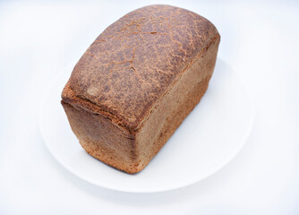 A black loaf of bread on a white background. Freshly baked bread.