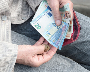 Euro banknotes in the hands of an elderly woman.	