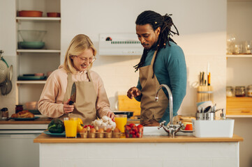 An affectionate interracial couple is cooking together at home.