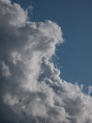 View of blue sky with fluffy white and dark clouds in a sunny day. Background of dark sky sunlit with beautiful white clouds