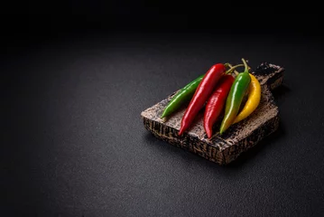 Poster Hot chili peppers of three different colors red, green and yellow © chernikovatv