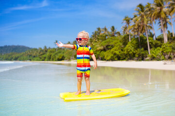 Obraz na płótnie Canvas Child surfing on tropical beach. Surfer in ocean.