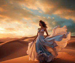 Schilderijen op glas Woman in satin dress on the desert, beautiful romantic girl on sunset dunes © AdamantiumStock