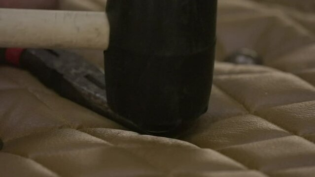 This close up video shows a hammer tufting leather furniture in slow motion.