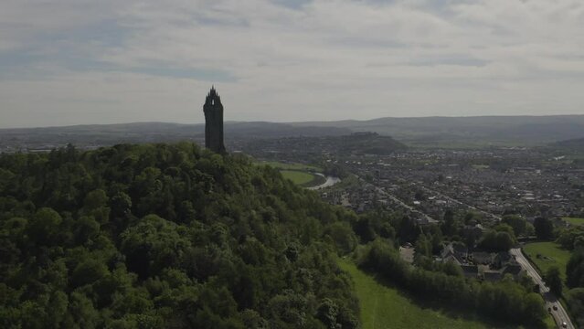 Wallace Monument scottish national landmark on Abeey Craig green hill with cityscape and nature landscape in background aerial view in Scotland, UK