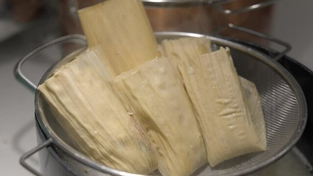 This video shows hands places tamales in a pot steamer.