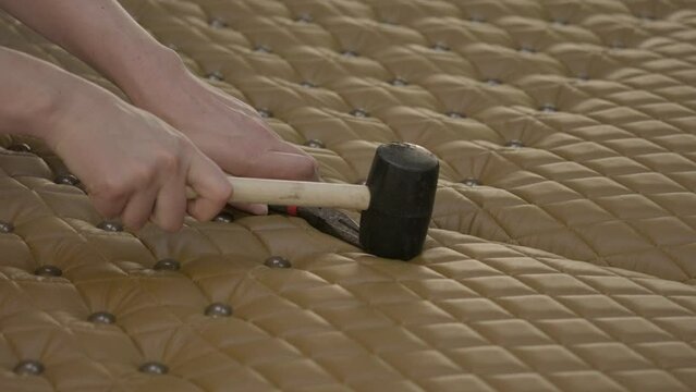This video shows hand using tacks and a mallet to tuft leather upholstery panels.
