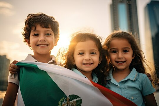Mexican kids holding the mexican flag with pride for the national day. Happy and joy kids south.