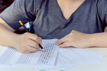 Students hand holding pencil writing selected choice on answer sheets and Mathematics question sheets. students testing doing examination. school exam - obrazy, fototapety, plakaty