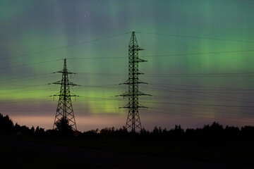 silhouettes of power lines against the background of the aurora