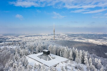 Aerial view of lush snow-covered woods with Avala Tower in the background. Beli Potok, Serbia.