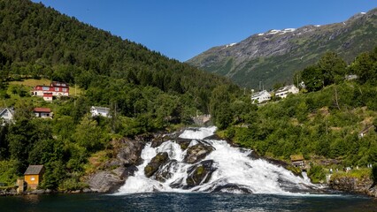 a waterfall falls over the edge of a large lake next to a small town