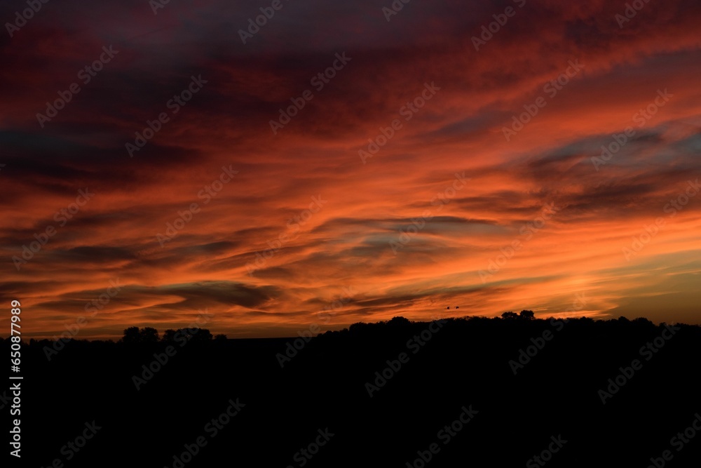 Wall mural Breathtaking sunset featuring vivid tones of orange and yellow with fluffy clouds