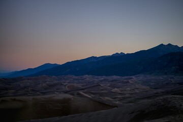 Picturesque view of a mountain range and surrounding desert landscape illuminated by the setting sun