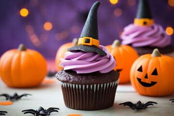 Halloween cupcakes with purple frosting and black witch hat topping with pumpkins in background - obrazy, fototapety, plakaty
