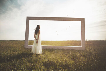 woman looks at the infinite beyond a surreal window in the middle of nature, concept of freedom beyond borders