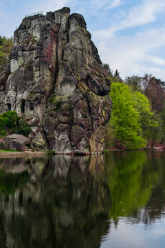 View of a rocky hill and the reflection on the lake in Externsteine, Germany