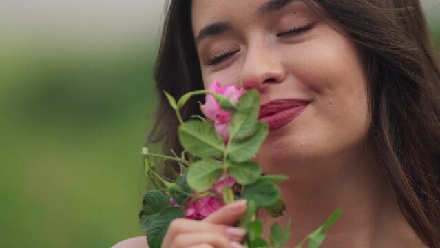 Pretty Caucasian girl smelling a pink flower, closeup shot