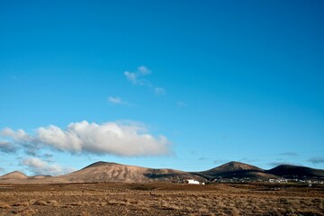 an empty field with dirt and mountains in the distance, in the far distance,