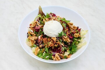 Lamb's lettuce, walnuts and goat cheese salad placed on a white plate