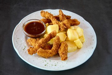 Appetising white plate with chicken fingers, french fries, and barbecue sauce