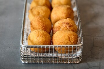 a metal basket filled with breaded pastries and butter