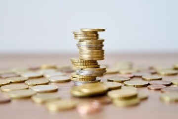 Pile of coins on a wooden table with shallow depth of field