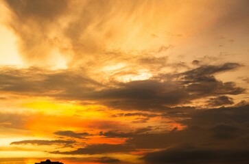 Vibrant orange sky at sunset illuminated with white and grey clouds