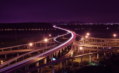 Fototapeta na wymiar Long exposure nighttime shot of a long winding road with multiple bridges spanning its length