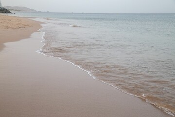 Calm sandy beach in the early morning with waves coming in