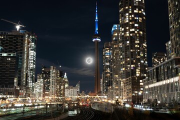 Fototapeta na wymiar Night view of Toronto city skyline illuminated by a full moon in the sky in Canada