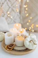Fototapeta na wymiar Autumn home decor with white pumpkins and burning aroma candles with sweet spicy pumpkin pie scent. Cozy fall composition, relaxation, aromatherapy. Apartment design, living room or bedroom