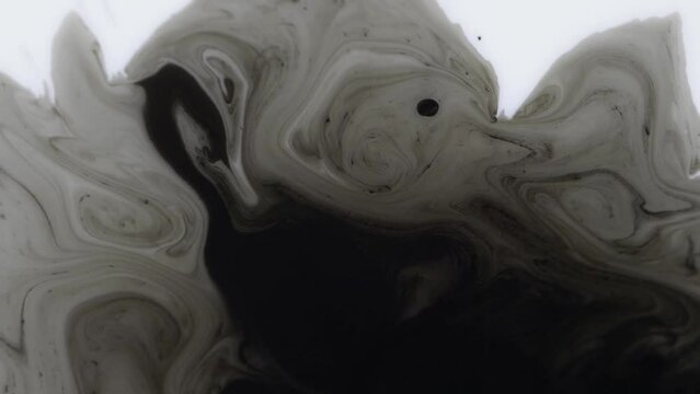 Closeup of a drop of black ink spreading in the liquid